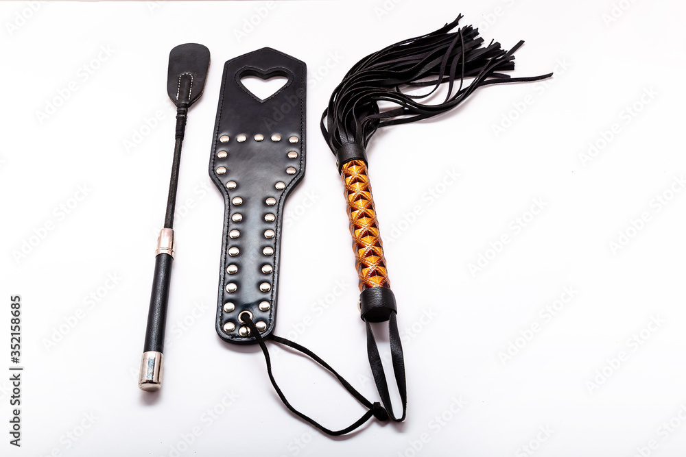 Whip on white background. Accessories for adult sexual games. Toys for BDSM,  spanking devices. Spanking and punishment concept. Slave Spank Paddle, bdsm,  adult whips. copy space. Set for bdsm Stock Photo |